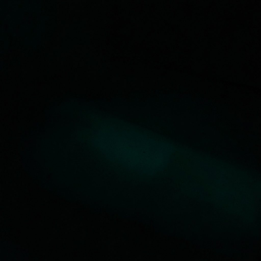 A dark, low-key overhead view of a long conference table with name placards in deep teal and charcoal tones, giving a scholarly mood.